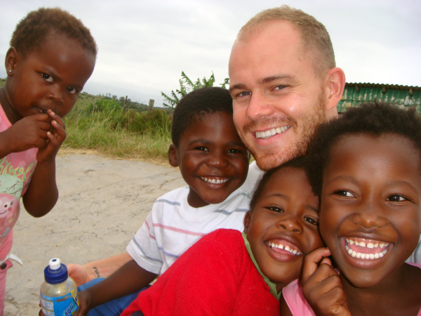 a volunteer abroad with children from a village where he is volunteering and living.