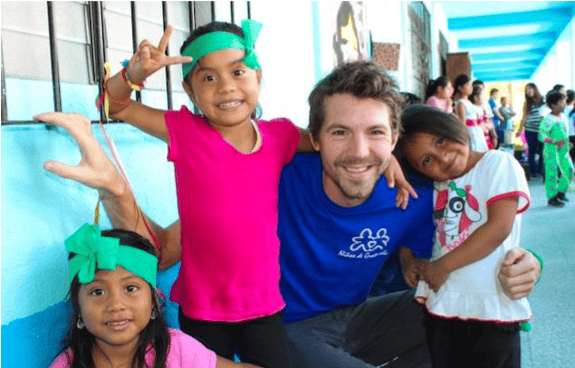 A GeoVisions volunteer in a school in Guatemala with 3 of his students.