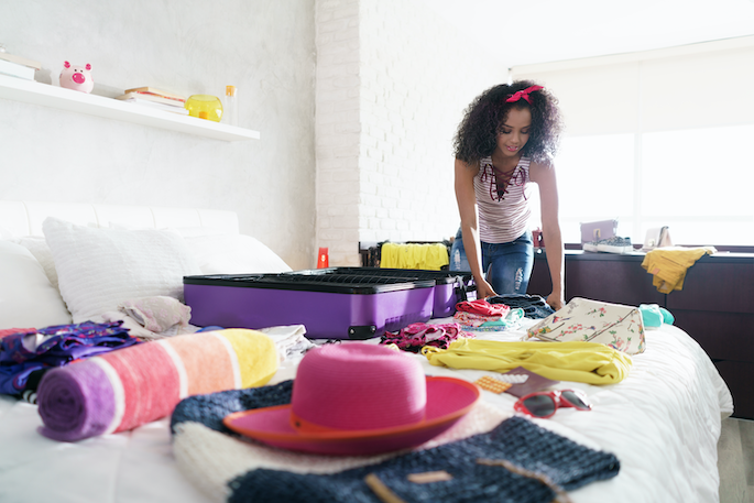 excited-young-black-woman-packing-bags-for-holidays-pretty-hispanic-girl-preparing-sui-SBI-330550216 copy