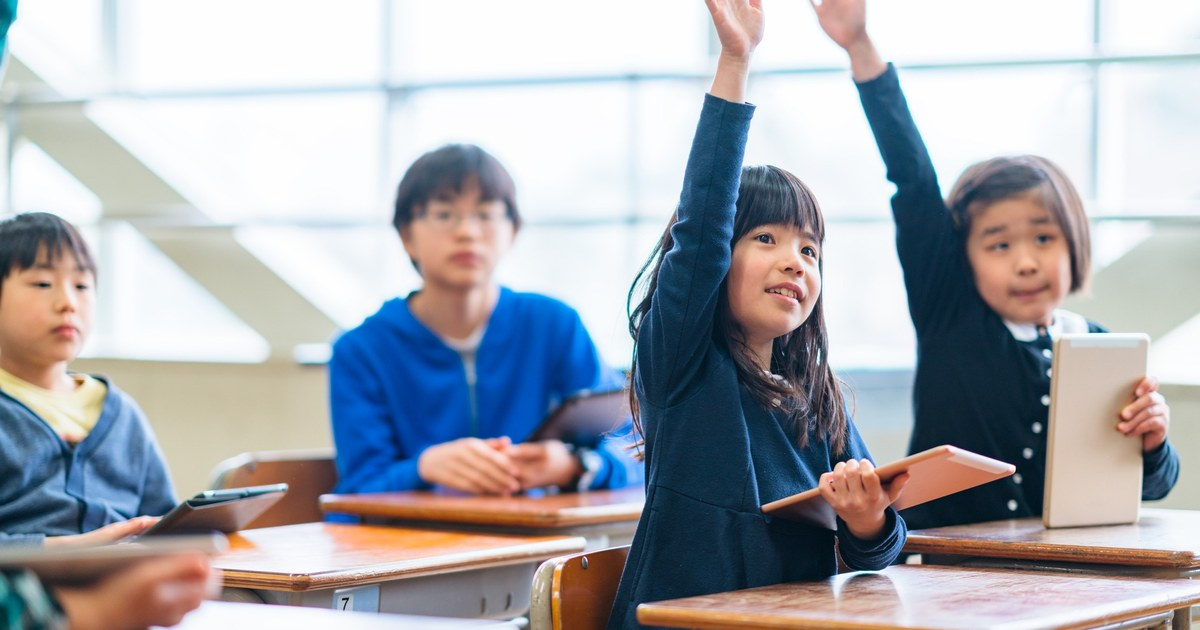 Students raising their hands in an English class in a South Korean school.