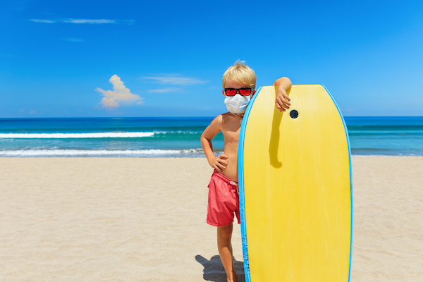 surfer boy on the beach with a covid-19 mask