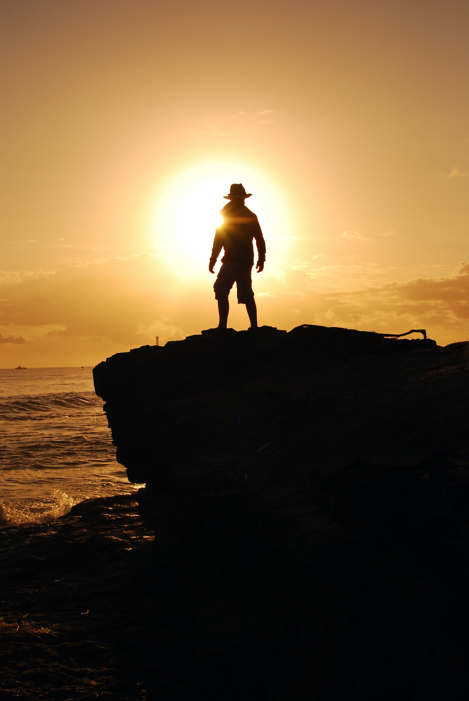 silhouette-of-man-in-hat-on-the-background-of-sunset-at-sea-SBI-305117987