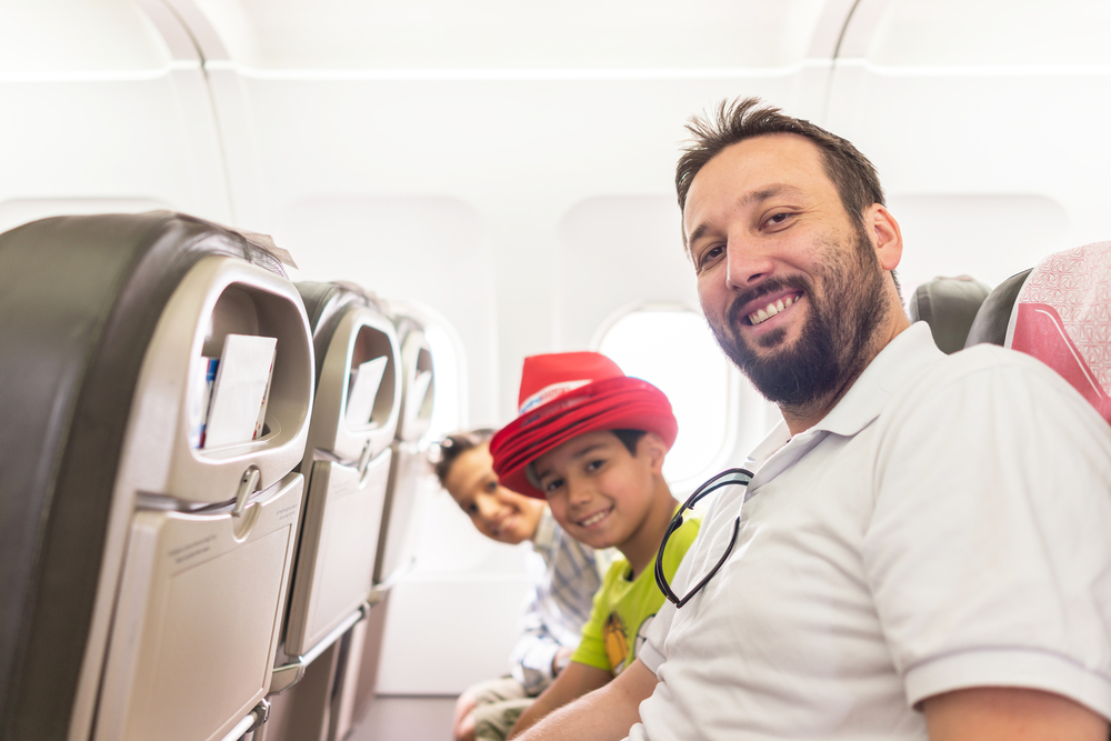 a father and his two sons in airplane seats waiting to take off and travel