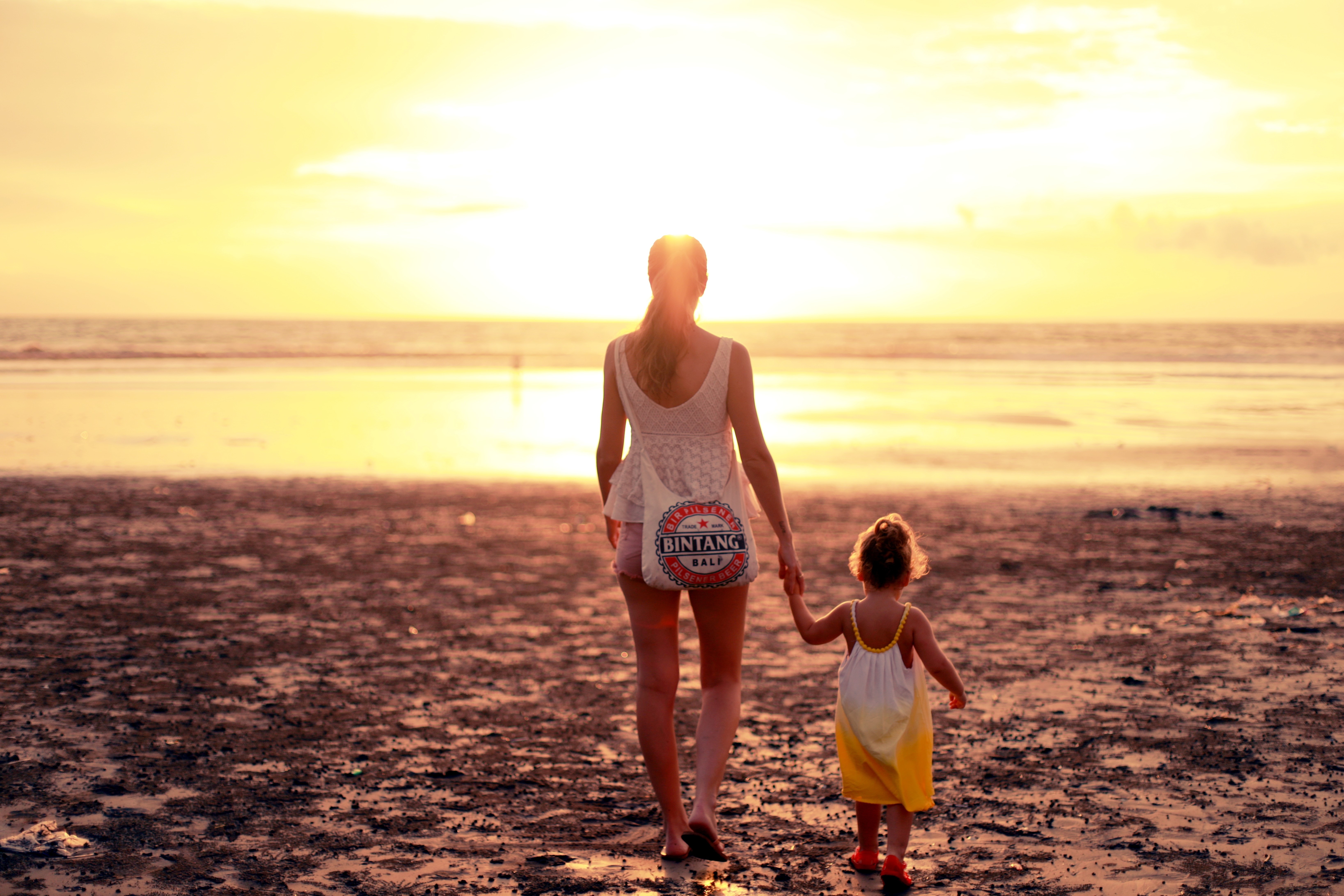 an au pair walking on the beach toward the ocean with her host sister